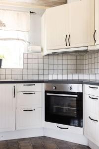 eine Küche mit weißen Schränken und einem schwarzen Backofen in der Unterkunft Holiday Home Skärvudde Huset - SND084 by Interhome in Kalvsvik