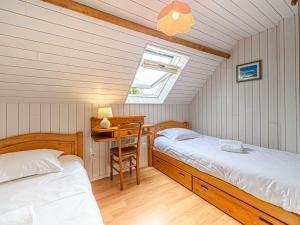 two beds in a room with a desk and a window at Holiday Home Maison de la Plage by Interhome in Carnac-Plage
