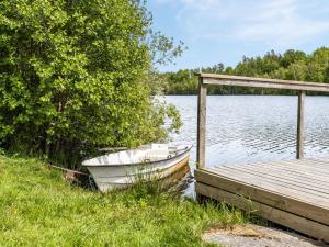 a boat sitting next to a dock on a lake at Holiday Home Gåragöl - B in Olofström