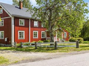 ein rotes Haus mit einem Baum und einem Zaun in der Unterkunft Holiday Home Gåragöl - B in Olofström