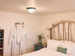 1 dormitorio con 1 cama con albornoces blancos en la pared en Little Bird Inn, en Margaretsville