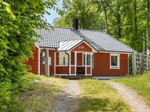 una cabaña roja en el bosque al lado de un camino de tierra en Holiday Home Erikstorp Fyran by Interhome, en Olofström