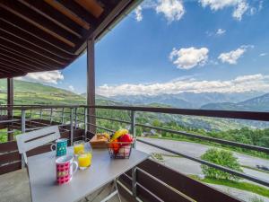 a table with a basket of food on a balcony with mountains at Apartment Les Pistes-16 by Interhome in Le Corbier