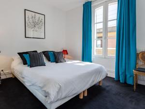 トゥルヴィル・シュル・メールにあるHoliday Home Guillaume le Conquérant by Interhomeのベッドルーム1室(青いカーテン、窓付)