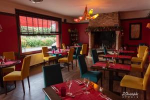 a dining room with tables and chairs and a fireplace at Logis - Hotel & Restaurant La Corne d 'Abondance in Bourgthéroulde