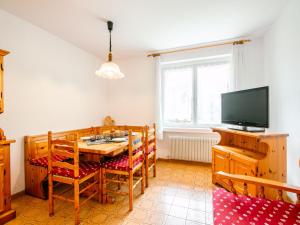 ein Esszimmer mit einem Tisch, Stühlen und einem TV in der Unterkunft Apartment Mantina-1 by Interhome in Moena