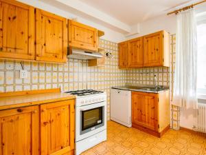 La cuisine est équipée de placards en bois et d'une cuisinière blanche. dans l'établissement Apartment Mantina-1 by Interhome, à Moena