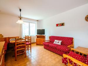 ein Wohnzimmer mit einem roten Sofa und einem Tisch in der Unterkunft Apartment Mantina-1 by Interhome in Moena
