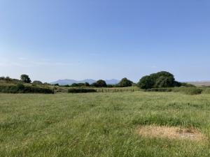 カーナーヴォンにあるHoliday Home Llanfaglan Farm by Interhomeの遠方の柵のある草原