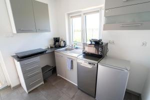 a small kitchen with a sink and a dishwasher at Apartamenty Tęczowa 14 Sarbinowo in Sarbinowo