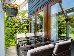 une véranda avec une table et des chaises en verre dans l'établissement Holiday Home De Schans by Interhome, à Anjum