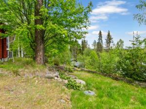 um jardim com uma árvore e pedras em frente a uma casa em Holiday Home Cjoe239 by Interhome em Pölläkkä