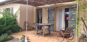 eine Terrasse mit einem Tisch und Stühlen darauf in der Unterkunft le coin de paradis in Modène