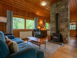 a living room with a blue couch and a fireplace at Holiday Home Kerrow Cottage by Interhome in Inverness