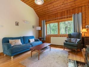 a living room with a blue couch and a table at Holiday Home Kerrow Cottage by Interhome in Inverness +35 photos