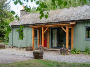 uma casa verde com uma porta vermelha e dois vasos de flores em Holiday Home Kerrow Cottage by Interhome em Inverness