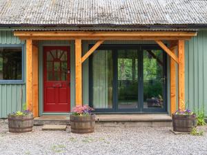 a house with a red door and two flower pots at Holiday Home Kerrow Cottage by Interhome in Inverness