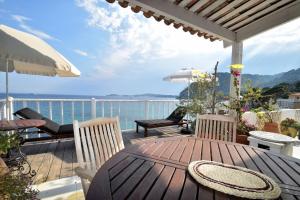 een houten tafel met stoelen en een parasol op een terras bij FRONT BEACH PENTHOUSE in Èze