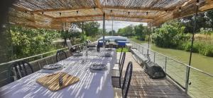 a long table on a deck next to a river at Jolie péniche canal du Midi in Vias
