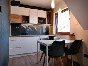 cocina con armarios blancos, mesa y sillas en Aster Aparts Wyspa Sobieszewska en Gdansk