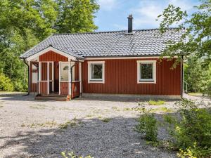 uma casa vermelha com uma garagem na floresta em Holiday Home Erikstorp Trean by Interhome em Olofström