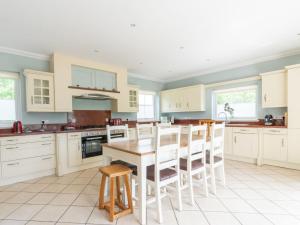 a kitchen with white cabinets and a table and chairs at Holiday Home Bearnock House by Interhome in Drumnadrochit