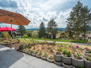 einen Garten mit Sonnenschirm und einigen Pflanzen in der Unterkunft Apartment Am Hohen Bogen-41 by Interhome in Arrach