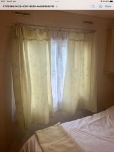 a window with white curtains next to a bed at Decker’s in Leven-Fife