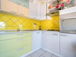 a kitchen with white cabinets and yellow tiles at Apartment Bruno by Interhome in Selce
