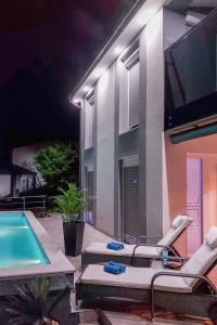 a house with a swimming pool and chairs and a tv at Holiday Home Emili & Elias by Interhome in Karlobag