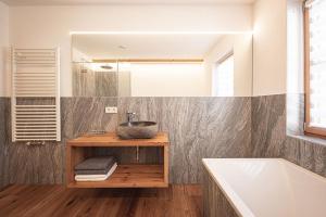 ein Badezimmer mit einem Waschbecken, einem Spiegel und einer Badewanne in der Unterkunft Kofler zw den Wänden Apt Zirm in Sand in Taufers