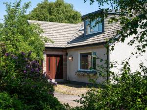 a small white house with a brown door at Holiday Home Birnam by Interhome in Drumnadrochit