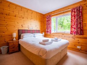 Un dormitorio con una cama grande en una habitación de madera. en Holiday Home Achmony Number 7 by Interhome, en Drumnadrochit