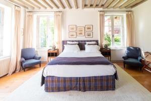a bedroom with a large bed and two blue chairs at Le Clos de Grâce in Honfleur
