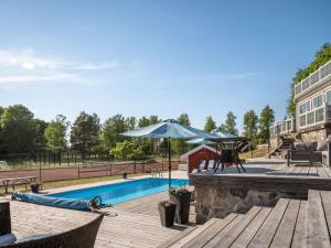 a pool with an umbrella next to a wooden deck at Holiday Home Skarpsätter Sportgård by Interhome in Strängnäs +38 photos
