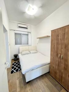 1 dormitorio con cama blanca y armario de madera en Bat Galim BEACH apartment en Haifa
