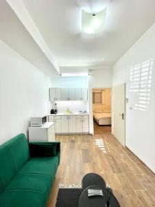 a living room with a green couch and a kitchen at Bat Galim BEACH apartment in Haifa