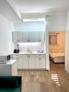 una cocina con armarios blancos y una habitación con cama en Bat Galim BEACH apartment en Haifa