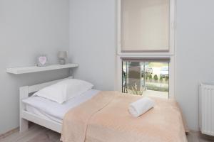 a white bedroom with a bed and a window at Turzycowa Apartment in Gdansk by Renters in Gdańsk