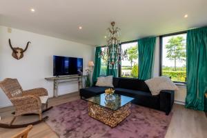 ein Wohnzimmer mit einer schwarzen Couch und einem Tisch in der Unterkunft Welcome in - Vakantiehuis Oostburgsestraat 44, Zuidzande in Zuidzande