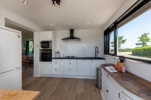 a kitchen with white cabinets and a large window at Vakantiehuis Oostburgsestraat 44, Zuidzande in Zuidzande