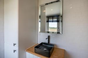 ein Badezimmer mit einem schwarzen Waschbecken und einem Spiegel in der Unterkunft Welcome in - Vakantiehuis Oostburgsestraat 44, Zuidzande in Zuidzande + 23 Fotos