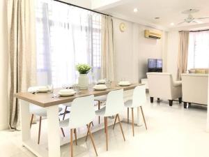a dining room with a table and white chairs at Family 4BR Landed House @ SPICE ARENA in Bayan Lepas