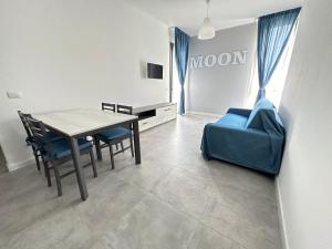 a dining room with a table and a blue couch at LUX apartments in Follonica