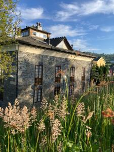 un vieux bâtiment en pierre dans un champ de gazon haut dans l'établissement Ahío San Martín, Apartamentos Rurales Casa de la Villa, à San Martín de Oscos