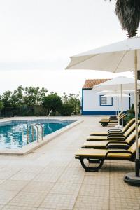 a swimming pool with lounge chairs and umbrellas at Humus Farm in Águas de Moura