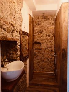 baño con lavabo blanco y pared de piedra en Gemma Maris, en Sapri