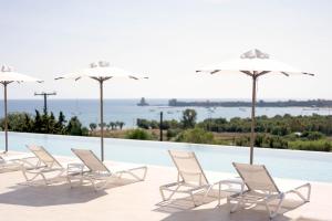 un gruppo di sedie e ombrelloni accanto alla piscina di Achilles Hill Hotel a Methoni