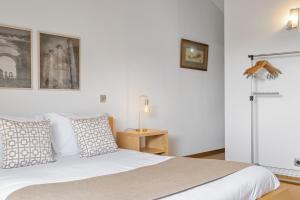 a white bedroom with a bed and a night stand at Casa Anaim by Homie in Lapeiras