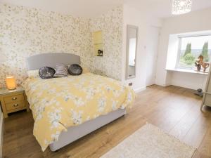 a bedroom with a bed with a yellow comforter and a window at Braeface Cottage in Bonnybridge